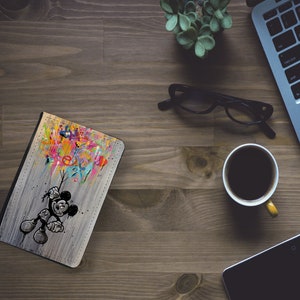 May include: A colourful, abstract design with Mickey Mouse holding onto a bunch of balloons. The design is on a grey, textured background.