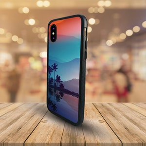 May include: A black phone case with a colorful sunset and palm trees reflected in water. The case has a black rubber bumper and a clear back.