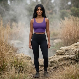 Può includere: Un top corto senza maniche viola con scollo rotondo abbinato a leggings neri a vita alta. L'abbigliamento è completato da scarpe da ginnastica grigie, creando un completo sportivo coordinato adatto per attività all'aperto e movimento.