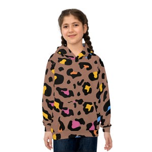 Può includere: Una felpa con cappuccio marrone con un motivo leopardato colorato. Il design presenta macchie nere, gialle, rosa, arancioni e blu. La felpa ha una tasca frontale e un cappuccio.