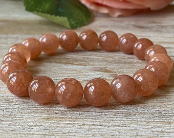 Op de afbeelding: Een armband gemaakt van ronde, lichtoranje carneol kralen. De kralen zijn glad en hebben een lichte glans.