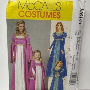 May include: McCall's Costumes sewing pattern M6141 for Miss and child sizes. The envelope features illustrations of two long dresses with empire waists, square necklines, and long sleeves. One dress is pink and white, the other is blue and patterned.