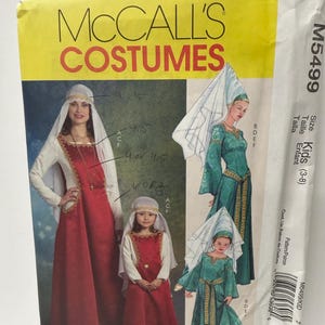 May include: McCall's Costumes sewing pattern M5499 for kids sizes 3-8. The envelope features illustrations of long dresses with gold trim, long sleeves, and headpieces in red and green. Handwritten notes are visible on the front.