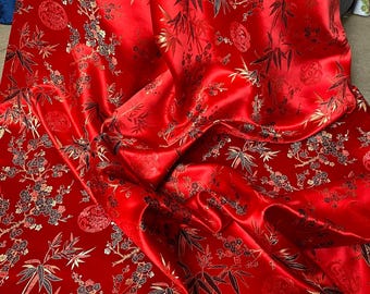 Könnte beinhalten: Roter Satin-Stoff mit einem goldenen und schwarzen Blumenmuster. Der Stoff zeigt ein sich wiederholendes Muster aus Bambuszweigen und Kirschblüten.
