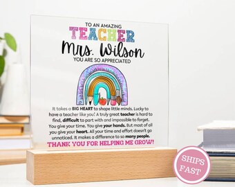 May include: A clear acrylic plaque with a wooden base, featuring text that reads "TO AN AMAZING TEACHER Mrs. Wilson YOU ARE SO APPRECIATED." A colorful rainbow illustration is above the text. The plaque includes a message of appreciation for teachers.