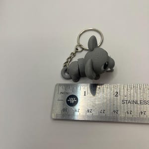 May include: A gray, 3D printed mouse keychain with a silver chain and ring. The mouse is about 1 inch long.