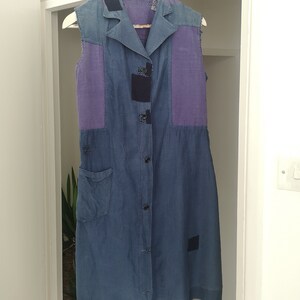 May include: A sleeveless blue and purple patchwork dress with a button-up front and a single pocket on the left side.