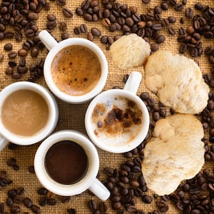 Pu&ograve; includere: Quattro tazze di ceramica bianca piene di caff&egrave;, circondate da chicchi di caff&egrave; su una superficie di juta marrone. Le tazze sono disposte a forma di quadrato, con due tazze su ogni lato. I chicchi di caff&egrave; sono sparsi intorno alle tazze, e alcuni sono persino all'interno delle tazze.