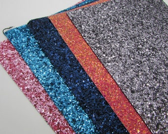 May include: Five different colors of glitter fabric swatches. The swatches are arranged in a row from left to right: pink, blue, dark blue, orange, and gray.
