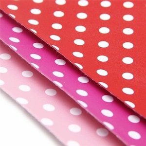 May include: Three sheets of paper with white polka dots on a red, pink, and light pink background.