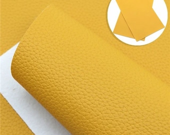 May include: A close-up of a sheet of yellow faux leather with a textured surface. The leather is rolled up and the edges are visible.