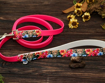Peut inclure: Une laisse pour chien rose et blanche avec un imprimé floral et guépard. La laisse a un clip argenté et est faite d'un matériau durable.