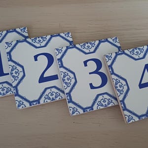 May include: Four white ceramic tiles with blue and white patterned designs. Each tile features a blue number, 1 through 4.