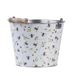 May include: White metal bucket with a wooden handle and a bee and floral pattern.