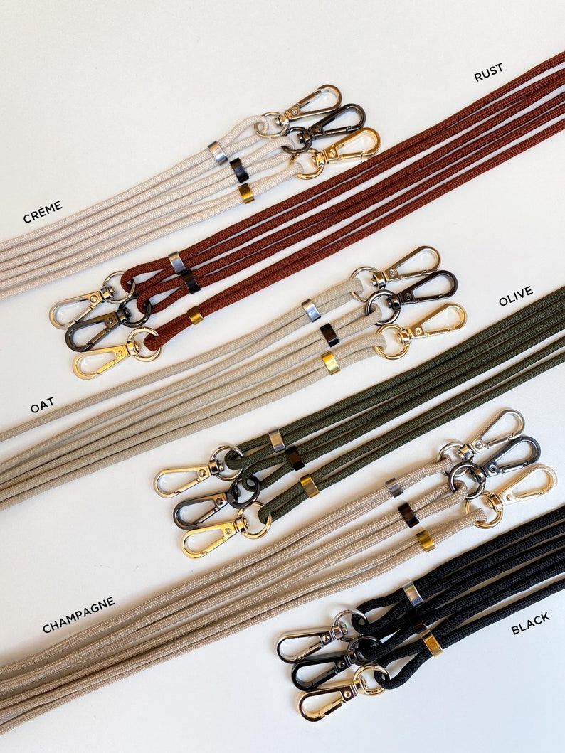 K&ouml;nnte beinhalten: Ein Set aus sechs verschiedenen farbigen Lanyards mit goldenen und silbernen Verschl&uuml;ssen. Die Farben sind Creme, Rost, Oliv, Hafer, Champagner und Schwarz.