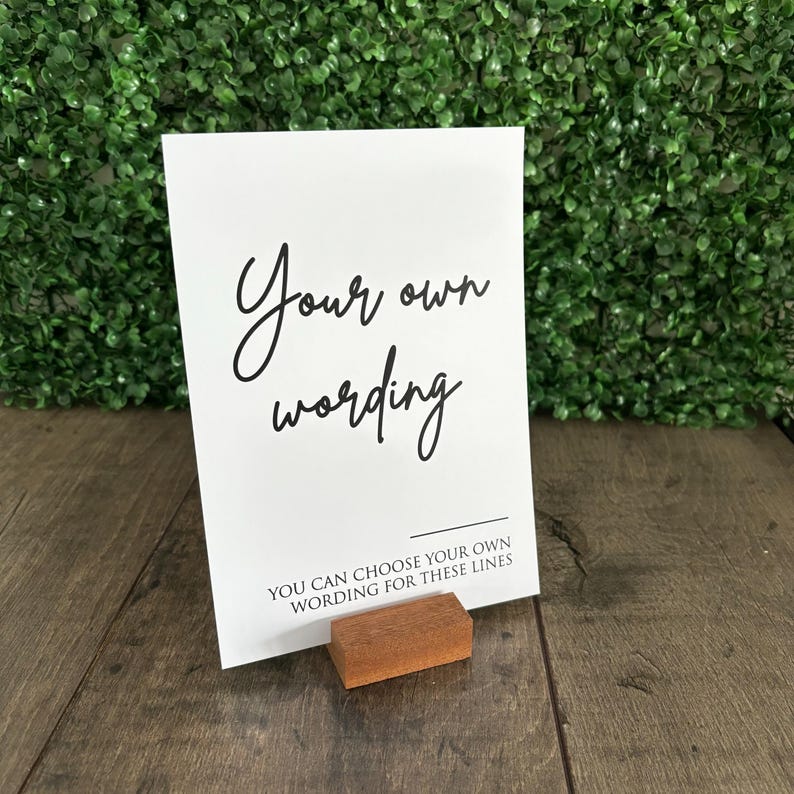 May include: White card with black text that reads "Your own wording" and "You can choose your own wording for these lines". The card is standing on a small wooden easel.