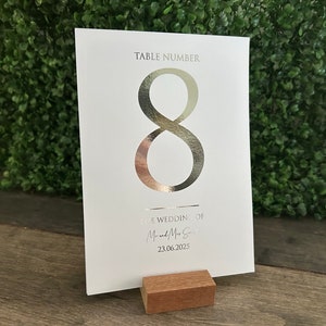 May include: White table number card with a silver foil number 8. The card has the text "Table Number" and "The Wedding of Mr. & Mrs. Smith 23.06.2025".
