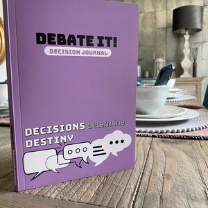 May include: Purple journal with the title "Debate It! Decision Journal" and the text "Decisions determine Destiny" with three speech bubbles.