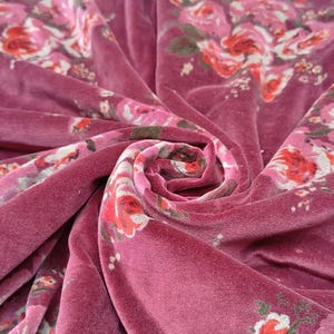May include: Pink velvet fabric with a floral pattern. The fabric is soft and luxurious, and the floral pattern is delicate and feminine.
