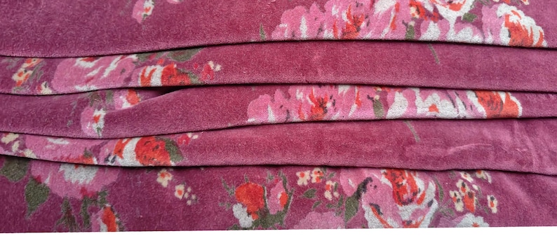 May include: Close-up of a folded fabric with a pink floral pattern. The fabric has a soft, velvety texture.