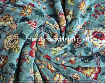 May include: A close-up of a floral fabric with a swirling pattern. The fabric features large flowers in shades of yellow, red, and orange against a muted teal background. The text "HandicraByHandicraft" is visible.