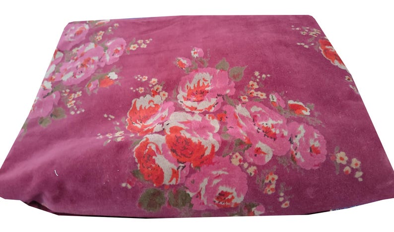 May include: A pink fabric with a floral pattern featuring pink, red, and white flowers. The fabric has a soft, velvety texture.