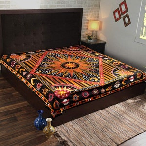 May include: A black and orange tapestry with a large sun design in the center. The tapestry is decorated with stars, moons, and other celestial symbols. It is draped over a bed frame.