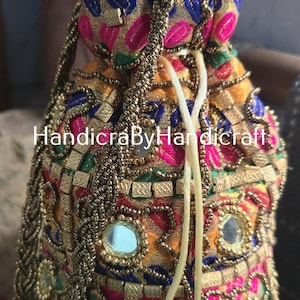 Könnte beinhalten: Ein verzierter Beutel mit Kordelzug, aufwendiger Stickerei und Verzierungen. Die Tasche weist eine lebendige Mischung aus Farben auf, darunter Gold, Rosa, Blau und Grün, mit Spiegelakzenten. Der Text "HandicraByHandicraft" ist sichtbar.
