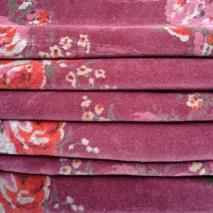 May include: Close-up of a folded fabric with a pink background and a floral pattern in shades of pink, red, and white.