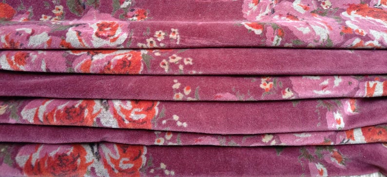 May include: Close-up of a folded fabric with a pink background and a floral pattern in shades of pink, red, and white.