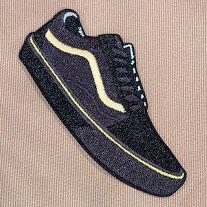 May include: Black and yellow embroidered patch of a classic low-top sneaker.