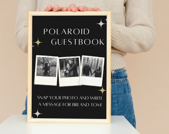 May include: A black chalkboard with the text "Polaroid Guestbook" in white. There are three black and white Polaroid photos of a couple in a forest. The text "Snap your photo and write a message for Bri and Tom!" is below the photos.