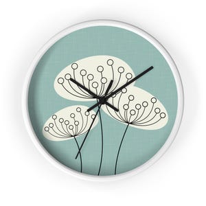Peut inclure: Une horloge murale blanche avec un fond bleu et un contour noir de trois fleurs stylisées avec des centres blancs. Les aiguilles de l'horloge sont noires.