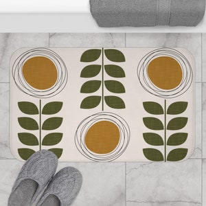 Peut inclure: Un tapis de bain blanc avec un motif géométrique de feuilles vertes et de cercles jaunes moutarde. Les cercles sont entourés de lignes noires.