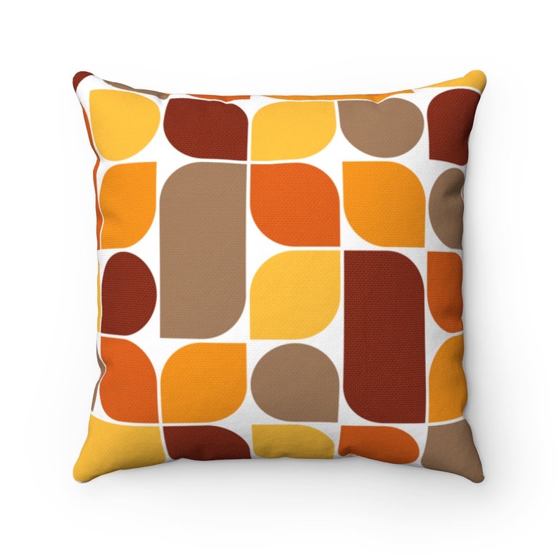 May include: Square throw pillow with a retro geometric pattern. The design features a repeating pattern of rounded shapes in shades of brown, orange, and yellow against a white background. The pillow has a textured appearance.