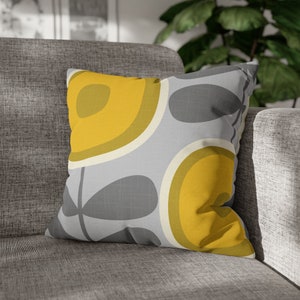 May include: A gray and yellow throw pillow with a geometric pattern of circles and leaves. The pillow is made of a soft, textured fabric.