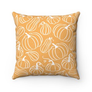 May include: Square throw pillow with a repeating pattern of white line-drawn pumpkins and gourds on an orange background. The pillow has a soft, inviting appearance, perfect for fall decor.