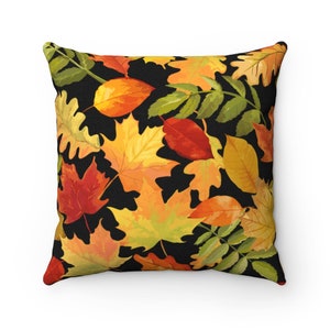 May include: Square throw pillow with a black background and a pattern of colorful autumn leaves in shades of red, orange, and yellow. The leaves are of various shapes and sizes, creating a seasonal design.