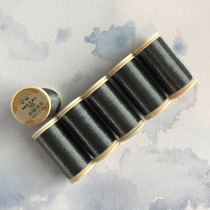 May include: Six spools of dark gray metallic thread, each with a white label that reads "No.40 Metal 165 176917 31184 AU CHINOIS".