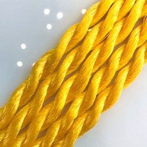 May include: Close-up of a bundle of bright yellow embroidery floss.