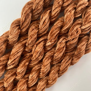 May include: Close-up of a bundle of brown chenille yarn. The yarn is soft and fluffy, and it is perfect for crocheting or knitting.