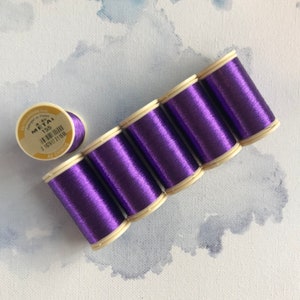 May include: Six spools of purple metallic thread, each with a label that reads "Fil Au Metal 135".