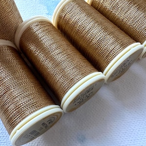 May include: Five spools of gold metallic thread, each with a white label that reads "Metallic" and "Made in Korea".