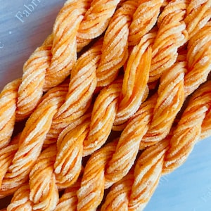 May include: Close-up of a bundle of orange velvet cord. The cord is soft and fluffy, and it is perfect for crafting projects.
