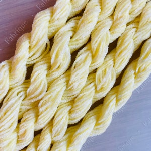 Peut inclure: Gros plan sur un paquet de fil chenille jaune pâle. Le fil est doux et moelleux, et il est parfait pour le crochet ou le tricot.