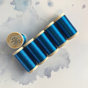 May include: Six spools of blue metallic thread, each with a white label. The label on one spool reads "N°40 METAL 280 159317 312884 40 CHNINGS".