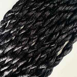 May include: Black braided rope with a textured surface. The rope is woven in a tight, intricate pattern.