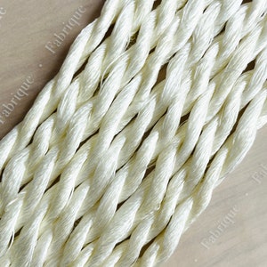 May include: Close-up of a bundle of white embroidery floss, showing the twisted strands of the thread.