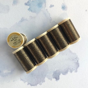 May include: Six spools of gold metallic thread, each with a label that reads "N 40 METAL 355".