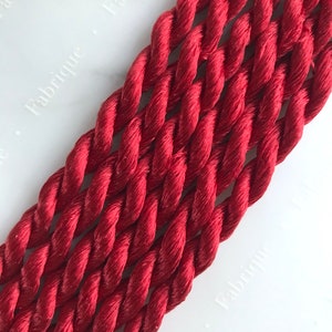 May include: Close-up of a red twisted cord, showing the texture and detail of the braided rope.